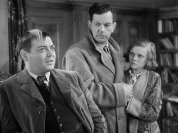 Movie still from “The Man Who Knew Too Much” (1934), directed by Alfred Hitchcock – A black - and - white photo of a man and a woman and another man; Medium shot, Over the shoulder angle