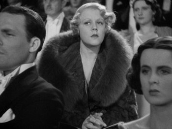 Movie still from “The Man Who Knew Too Much” (1934), directed by Alfred Hitchcock – An old photo of a woman wearing a fur coat; Medium shot, Over the shoulder angle