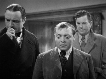 Movie still from “The Man Who Knew Too Much” (1934), directed by Alfred Hitchcock – Three men in suits and ties standing next to each other; Medium shot, Over the shoulder angle