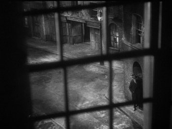 Movie still from “The Man Who Knew Too Much” (1934), directed by Alfred Hitchcock – A man standing in a courtyard looking out a window; Extreme Wide shot, High angle