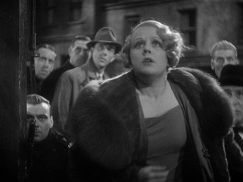 Movie still from “The Man Who Knew Too Much” (1934), directed by Alfred Hitchcock – An old photo of a group of people on a street; Medium shot, Low angle