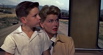 Movie still from “The Man Who Knew Too Much” (1956), directed by Alfred Hitchcock – A woman and a young boy are looking at a screen; Medium shot, Low angle