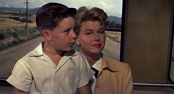 Movie still from “The Man Who Knew Too Much” (1956), directed by Alfred Hitchcock – A woman and a young boy standing next to each other; Medium shot, Over the shoulder angle