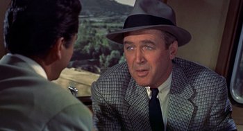 Movie still from “The Man Who Knew Too Much” (1956), directed by Alfred Hitchcock – A man in a hat and a suit talking to another man in a hat; Close Up shot, Over the shoulder angle