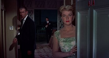 Movie still from “The Man Who Knew Too Much” (1956), directed by Alfred Hitchcock – A woman standing in front of two men in a room; Medium shot, Low angle