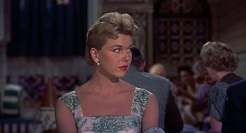 Movie still from “The Man Who Knew Too Much” (1956), directed by Alfred Hitchcock – A woman in a floral dress looking to her left; Close Up shot, Over the shoulder angle