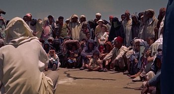 Movie still from “The Man Who Knew Too Much” (1956), directed by Alfred Hitchcock – A large group of people sitting on the ground; Wide shot, High angle