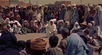 Movie still from “The Man Who Knew Too Much” (1956), directed by Alfred Hitchcock – A group of people gathered around a man in a white robe; Wide shot, High angle