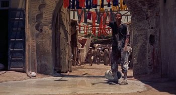 Movie still from “The Man Who Knew Too Much” (1956), directed by Alfred Hitchcock – A man standing in front of an open door with laundry hanging in the background; Wide shot, Low angle