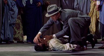Movie still from “The Man Who Knew Too Much” (1956), directed by Alfred Hitchcock – A man in a suit and a hat on the ground with another man in a suit and a hat; Medium shot, Overhead angle