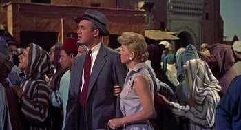 Movie still from “The Man Who Knew Too Much” (1956), directed by Alfred Hitchcock – A man and a woman standing next to each other in a crowd; Medium shot, Low angle
