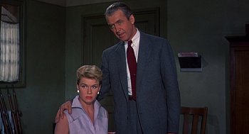 Movie still from “The Man Who Knew Too Much” (1956), directed by Alfred Hitchcock – A man standing next to a woman in a room; Medium shot, Low angle