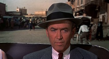 Movie still from “The Man Who Knew Too Much” (1956), directed by Alfred Hitchcock – A person wearing a suit and a hat; Close Up shot, Over the shoulder angle