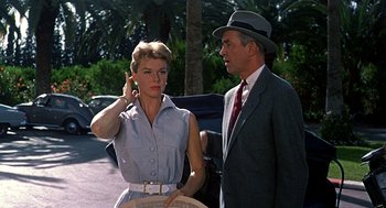 Movie still from “The Man Who Knew Too Much” (1956), directed by Alfred Hitchcock – A man and a woman standing next to each other on the street; Medium shot, Over the shoulder angle