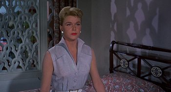 Movie still from “The Man Who Knew Too Much” (1956), directed by Alfred Hitchcock – A woman sitting on top of a bed in a room; Medium shot, Low angle