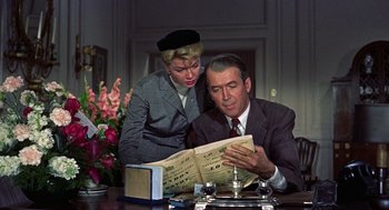 Movie still from “The Man Who Knew Too Much” (1956), directed by Alfred Hitchcock – A man and a woman are looking at a book; Medium shot, Low angle