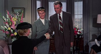 Movie still from “The Man Who Knew Too Much” (1956), directed by Alfred Hitchcock – A man and a woman shaking hands with a woman in a suit; Medium shot, Low angle