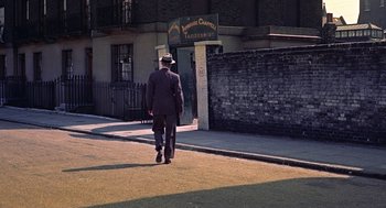 Movie still from “The Man Who Knew Too Much” (1956), directed by Alfred Hitchcock – A man in a suit and hat walking down the street; Wide shot, High angle