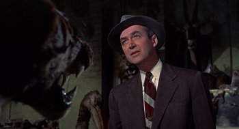 Movie still from “The Man Who Knew Too Much” (1956), directed by Alfred Hitchcock – A man in a suit and hat looking at a cat; Close Up shot, Low angle