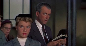 Movie still from “The Man Who Knew Too Much” (1956), directed by Alfred Hitchcock – A man and a woman are sitting next to each other holding a book; Close Up shot, Low angle