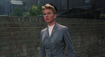 Movie still from “The Man Who Knew Too Much” (1956), directed by Alfred Hitchcock – A woman wearing a suit and a white shirt; Medium shot, Low angle
