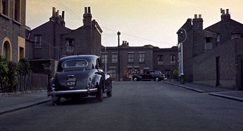 Movie still from “The Man Who Knew Too Much” (1956), directed by Alfred Hitchcock – An old car is parked in the middle of the street; Extreme Wide shot, High angle