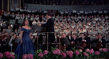 Movie still from “The Man Who Knew Too Much” (1956), directed by Alfred Hitchcock – A woman in a blue dress singing in front of an orchestra; Wide shot, Low angle
