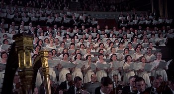 Movie still from “The Man Who Knew Too Much” (1956), directed by Alfred Hitchcock – A large group of people in white dresses holding musical instruments; Extreme Wide shot, High angle