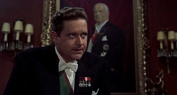 Movie still from “The Man Who Knew Too Much” (1956), directed by Alfred Hitchcock – A man in a suit and tie next to a painting; Close Up shot, Over the shoulder angle