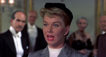 Movie still from “The Man Who Knew Too Much” (1956), directed by Alfred Hitchcock – A person wearing a suit and a hat; Close Up shot, Over the shoulder angle