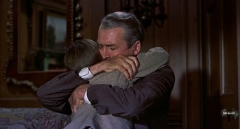 Movie still from “The Man Who Knew Too Much” (1956), directed by Alfred Hitchcock – An older man hugging a younger man in a room; Medium shot, Low angle