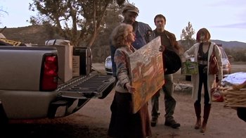 Movie still from “The Man from Earth” (2007), directed by Richard Schenkman – A woman holding a painting while standing next to two other people; Medium shot, Over the shoulder angle