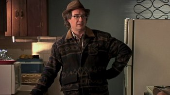 Movie still from “The Man from Earth” (2007), directed by Richard Schenkman – A man wearing a hat standing next to a refrigerator; Medium shot, Over the shoulder angle