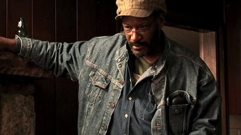 Movie still from “The Man from Earth” (2007), directed by Richard Schenkman – A man in a hat and glasses is standing in front of a wall; Close Up shot, Low angle
