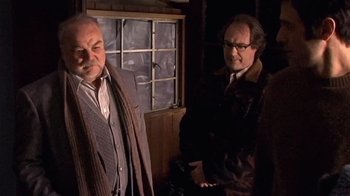 Movie still from “The Man from Earth” (2007), directed by Richard Schenkman – Two men standing next to each other near a window; Medium shot, Low angle