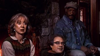 Movie still from “The Man from Earth” (2007), directed by Richard Schenkman – A group of people sitting next to each other in front of a stone wall; Medium shot, High angle