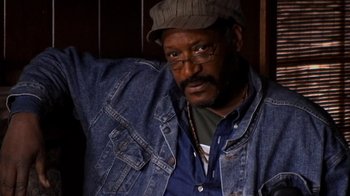 Movie still from “The Man from Earth” (2007), directed by Richard Schenkman – A person wearing a jean jacket and a hat; Close Up shot, High angle