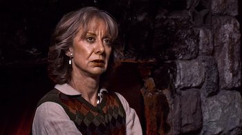 Movie still from “The Man from Earth” (2007), directed by Richard Schenkman – An older woman wearing a sweater and a vest; Close Up shot, Low angle