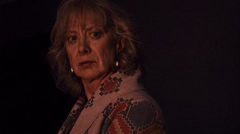 Movie still from “The Man from Earth” (2007), directed by Richard Schenkman – An older woman wearing a colorful jacket in the dark; Close Up shot, Low angle