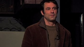 Movie still from “The Man from Earth” (2007), directed by Richard Schenkman – A person wearing a brown jacket; Medium shot, High angle