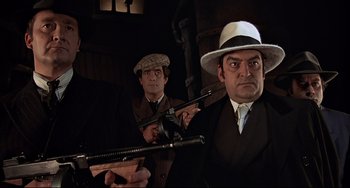 Movie still from “The Man with the Golden Gun” (1974), directed by Guy Hamilton – Two men in suits and hats are holding guns; Medium shot, Low angle