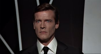 Movie still from “The Man with the Golden Gun” (1974), directed by Guy Hamilton – A person wearing a suit and tie; Close Up shot, Over the shoulder angle