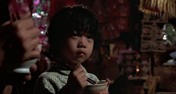 Movie still from “The Man with the Golden Gun” (1974), directed by Guy Hamilton – A little girl is holding a bowl of food; Close Up shot, Over the shoulder angle