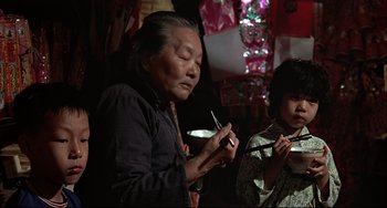 Movie still from “The Man with the Golden Gun” (1974), directed by Guy Hamilton – An older woman holding a pen and a young girl holding a spoon; Medium shot, Low angle