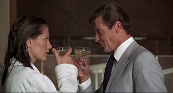 Movie still from “The Man with the Golden Gun” (1974), directed by Guy Hamilton – A man and a woman are holding wine glasses; Medium shot, Over the shoulder angle