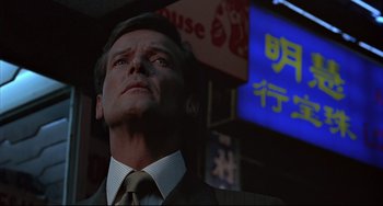 Movie still from “The Man with the Golden Gun” (1974), directed by Guy Hamilton – A man in a suit and tie looking up at the sky; Close Up shot, Low angle