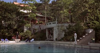 Movie still from “The Man with the Golden Gun” (1974), directed by Guy Hamilton – A man in a white shirt is swimming in a pool; Extreme Wide shot, High angle