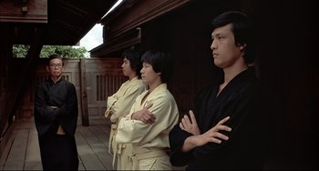 Movie still from “The Man with the Golden Gun” (1974), directed by Guy Hamilton – A group of men standing next to each other; Medium shot, Low angle