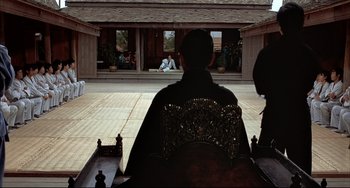 Movie still from “The Man with the Golden Gun” (1974), directed by Guy Hamilton – Two people sitting in a carriage in a courtyard; Wide shot, Over the shoulder angle
