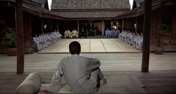Movie still from “The Man with the Golden Gun” (1974), directed by Guy Hamilton – A group of men sitting on a wooden floor; Extreme Wide shot, High angle